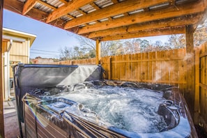 A hot tub under a wooden pergola with a wooden fence in the background. - Hot tub, Lego wall, theater room! 3 bedrooms, 2 bathrooms, near Dollywood! (Sevierville)