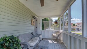 Eine überdachte Veranda mit Korbmöbeln, einem Deckenventilator und Blick auf die Nachbarschaft.