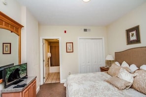 A hotel room with a bed, a television, a door, and a framed picture on the wall. - 1103 Golf View Towers Smoky Bear (Pigeon Forge)
