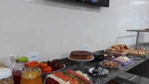 A buffet with various food items including fruits, cheeses, and pastries. - Colonia de Férias Sitraemfa (Peruíbe)