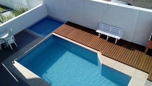 A swimming pool with a wooden deck and a white bench. - Colonia de Férias Sitraemfa (Peruíbe)