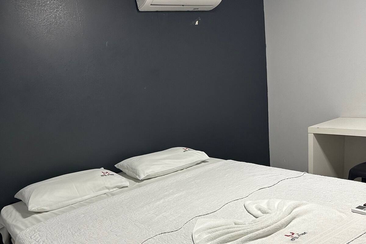 Ein Hotelzimmer mit Bett, Kissen, Handtuch und Klimaanlage.