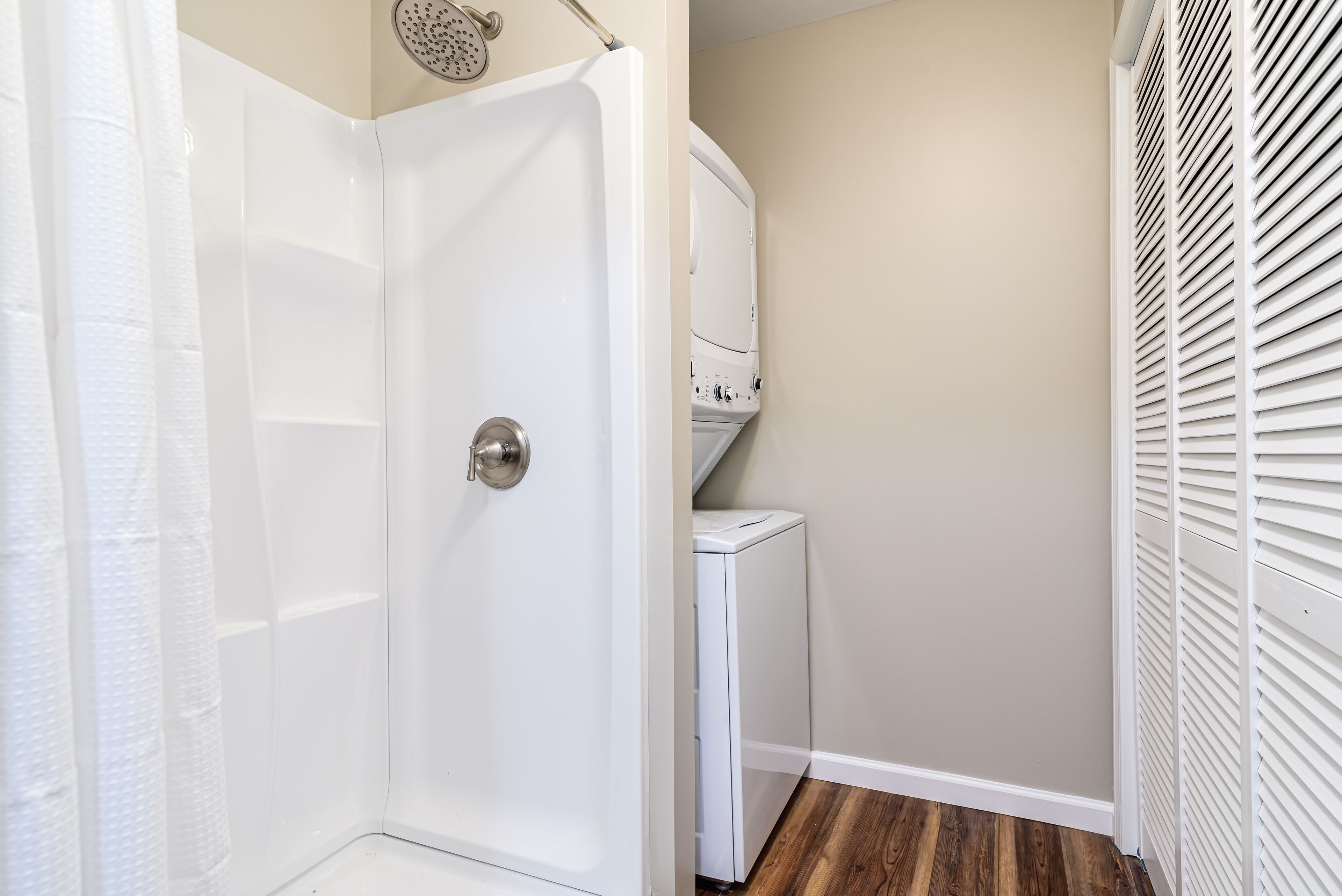 A bathroom with a shower, a toilet, and a washing machine.