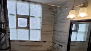 A bathroom with a bathtub, a vanity with a mirror, and a window.
