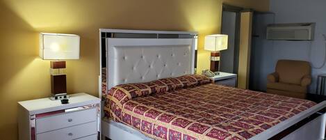 A neatly arranged bedroom with a large bed, bedside tables, a chair, and a radiator.