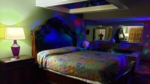 A bedroom with a bed, a nightstand, a lamp, and a mirror.