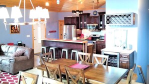 A cozy living room with a sofa and a dining area with a wooden table and chairs. - Blue Pine Lodge  - w/ Hot Tub - What a Mountain Cabin Should Be! (McGaheysville)