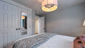 Een slaapkamer met een groot bed, een hanglamp en een garderobe.