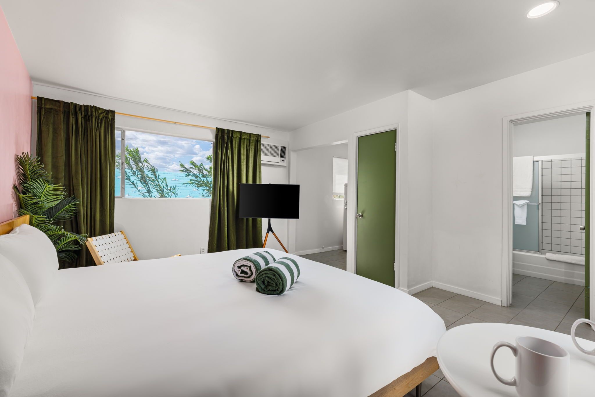 A hotel room with a bed, a TV, a coffee table, and a view of the sea.