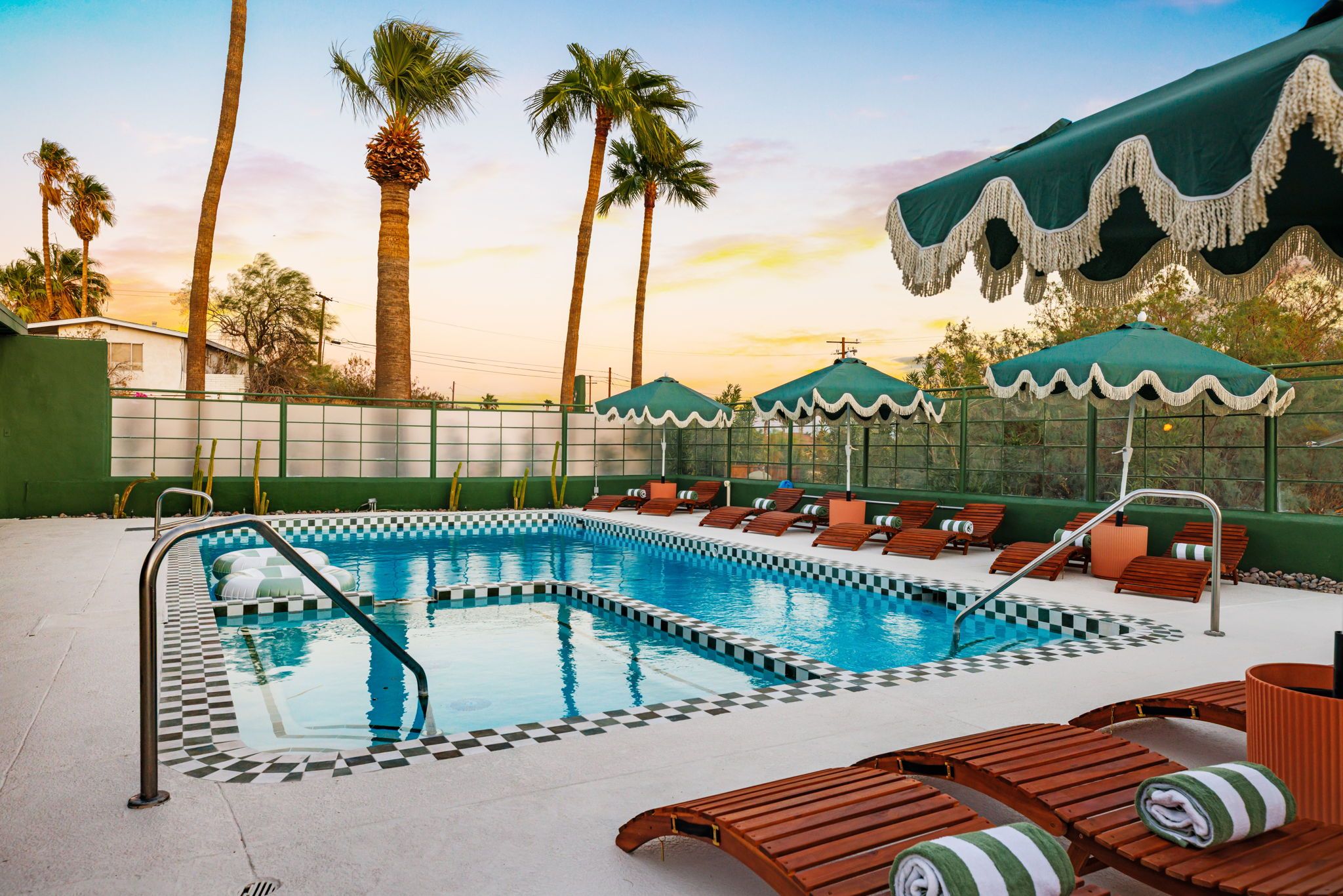 A swimming pool with checkered tiles, surrounded by lounge chairs and umbrellas.