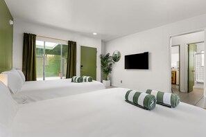 Habitación de hotel con dos camas, un televisor de pantalla plana, una planta en maceta y vistas al exterior.