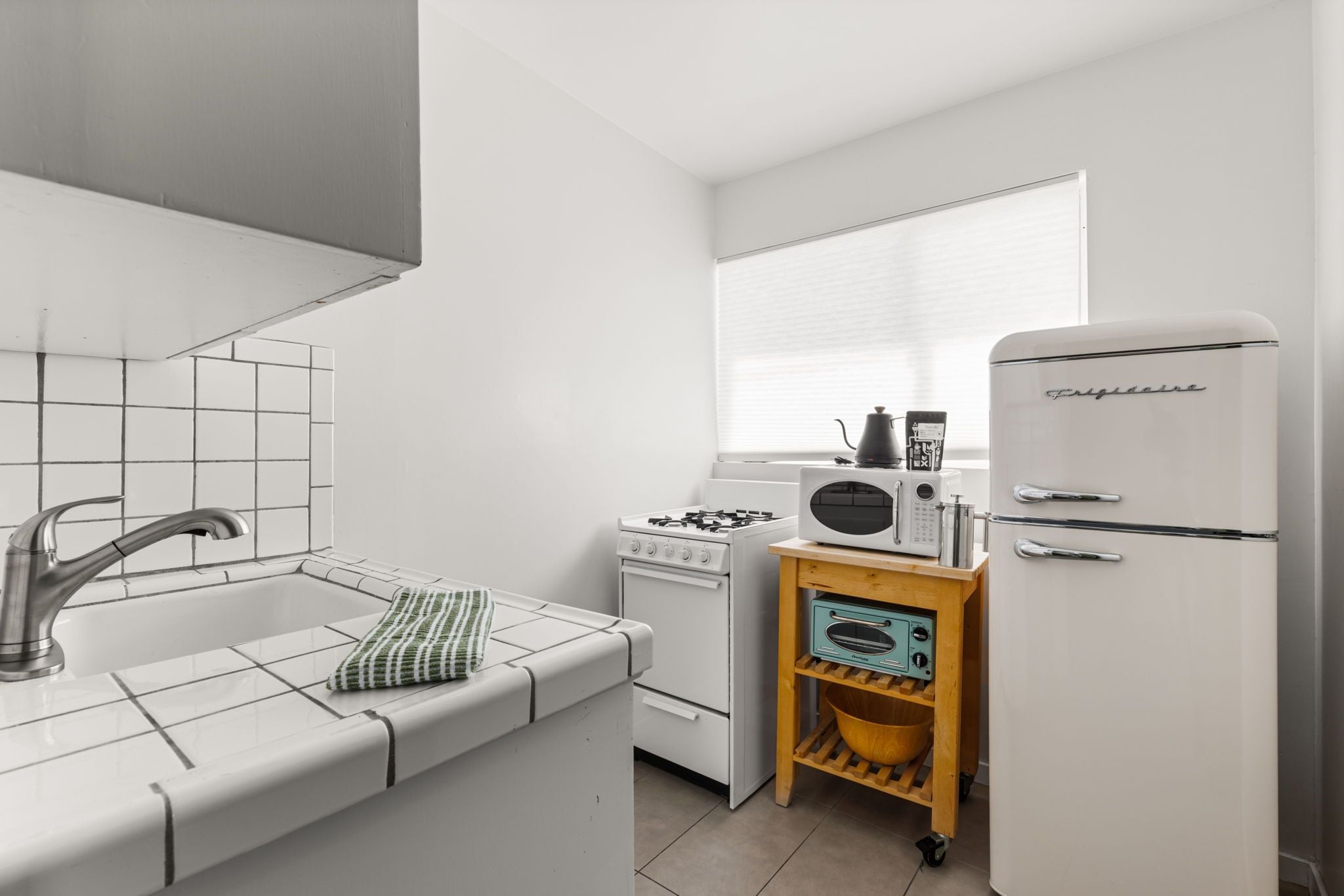 A compact kitchen with a gas stove, oven, microwave, and a refrigerator.