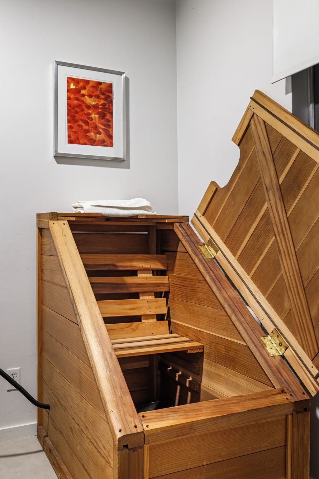 A wooden staircase with a built-in bench and a framed artwork on the wall.