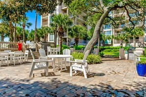 Relax in style with Adirondack chairs and a round table amidst lush greenery and a tropical ambiance.
