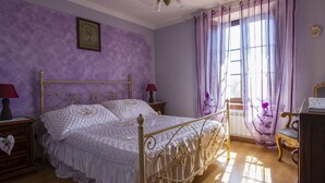 Une chambre à coucher avec un lit, des tables de chevet, une commode et une fenêtre avec des rideaux.