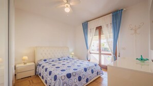A bedroom with a bed, a nightstand, a dresser, a ceiling fan, and a window with curtains. - Beautiful apartment for 5 guests with A/C, TV and balcony (Camaiore)