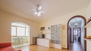 A spacious living area with a ceiling fan, a dining table with chairs, a kitchen area with cabinets, and a hallway leading to another room. - Beautiful apartment for 5 guests with A/C, TV and balcony (Camaiore)