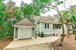 A two-story house with a garage, a front porch, and a wooden deck.