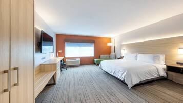 Une chambre d’hôtel avec un lit, un bureau, une chaise, une télévision et une fenêtre.