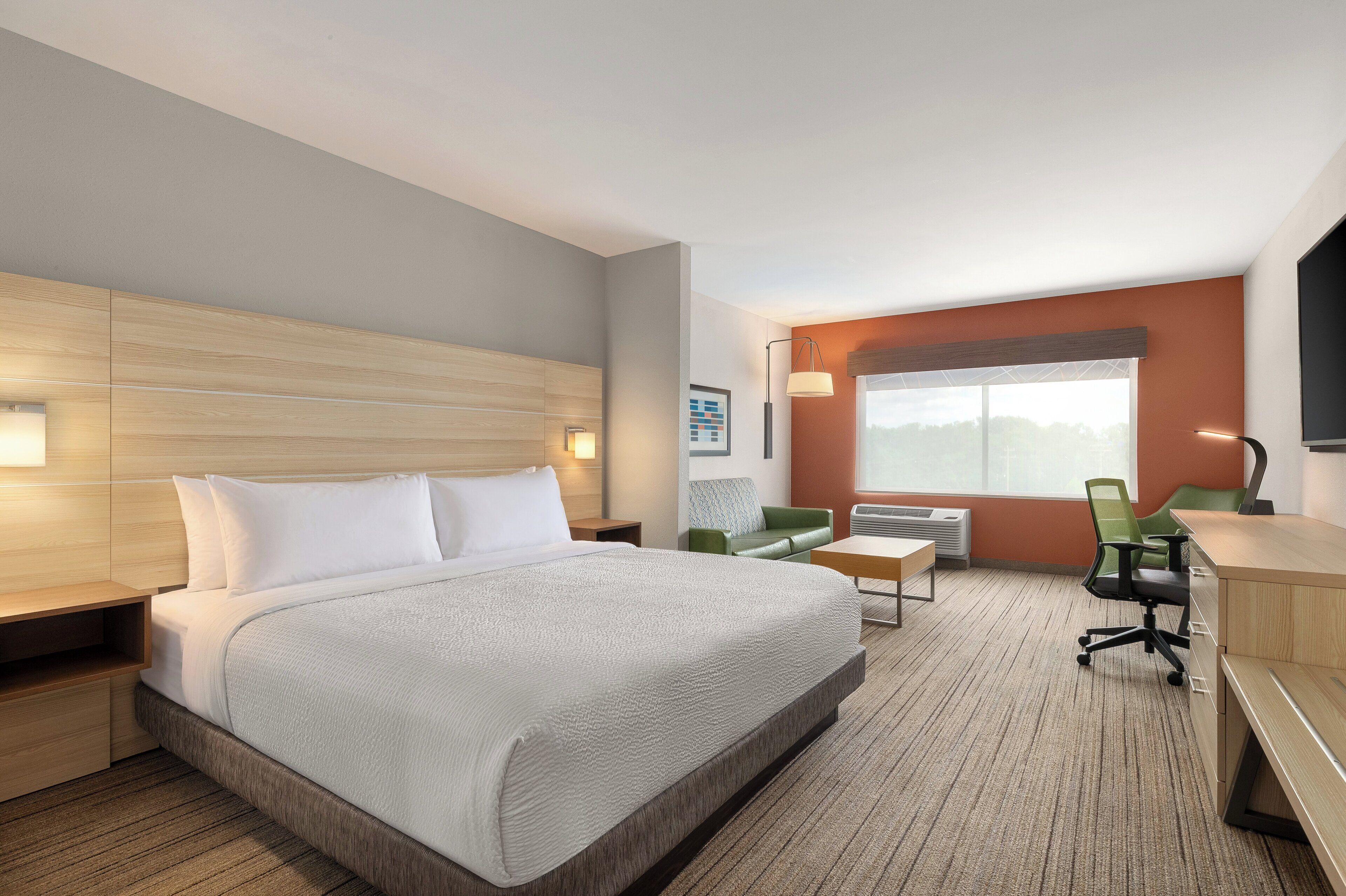 A hotel room with a bed, a desk, a chair, and a window.