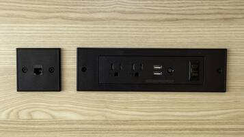 A black electrical outlet and switchboard with multiple ports and switches on a wooden surface.