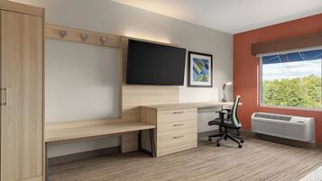 A modern bedroom with a wooden desk, a flat-screen TV, a framed picture, and a window with a view.