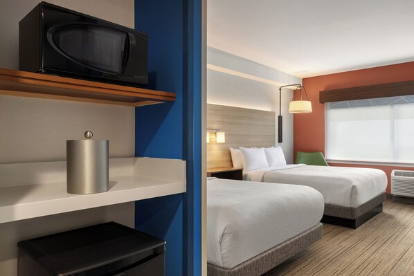 Habitación de hotel con dos camas, televisión, lámpara y ventana con vistas.