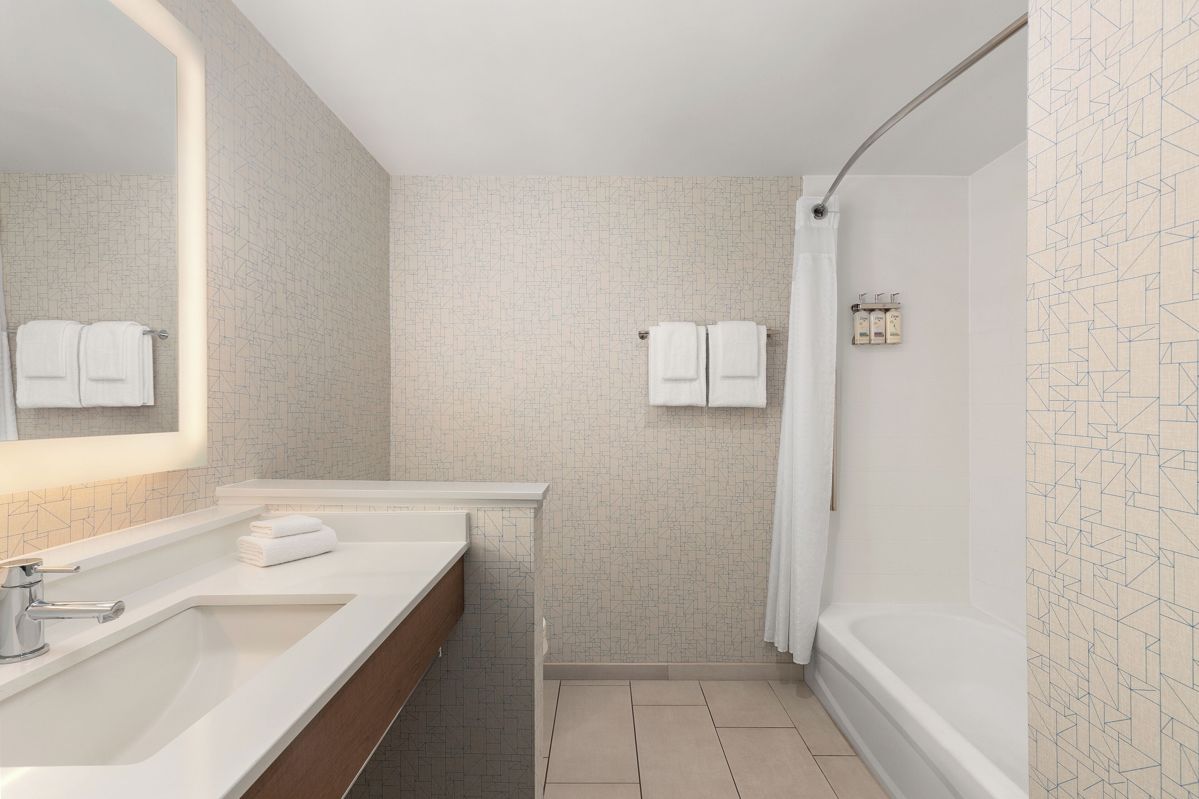 Un baño moderno con un espejo grande, dos lavamanos, una ducha y un perchero para toallas.