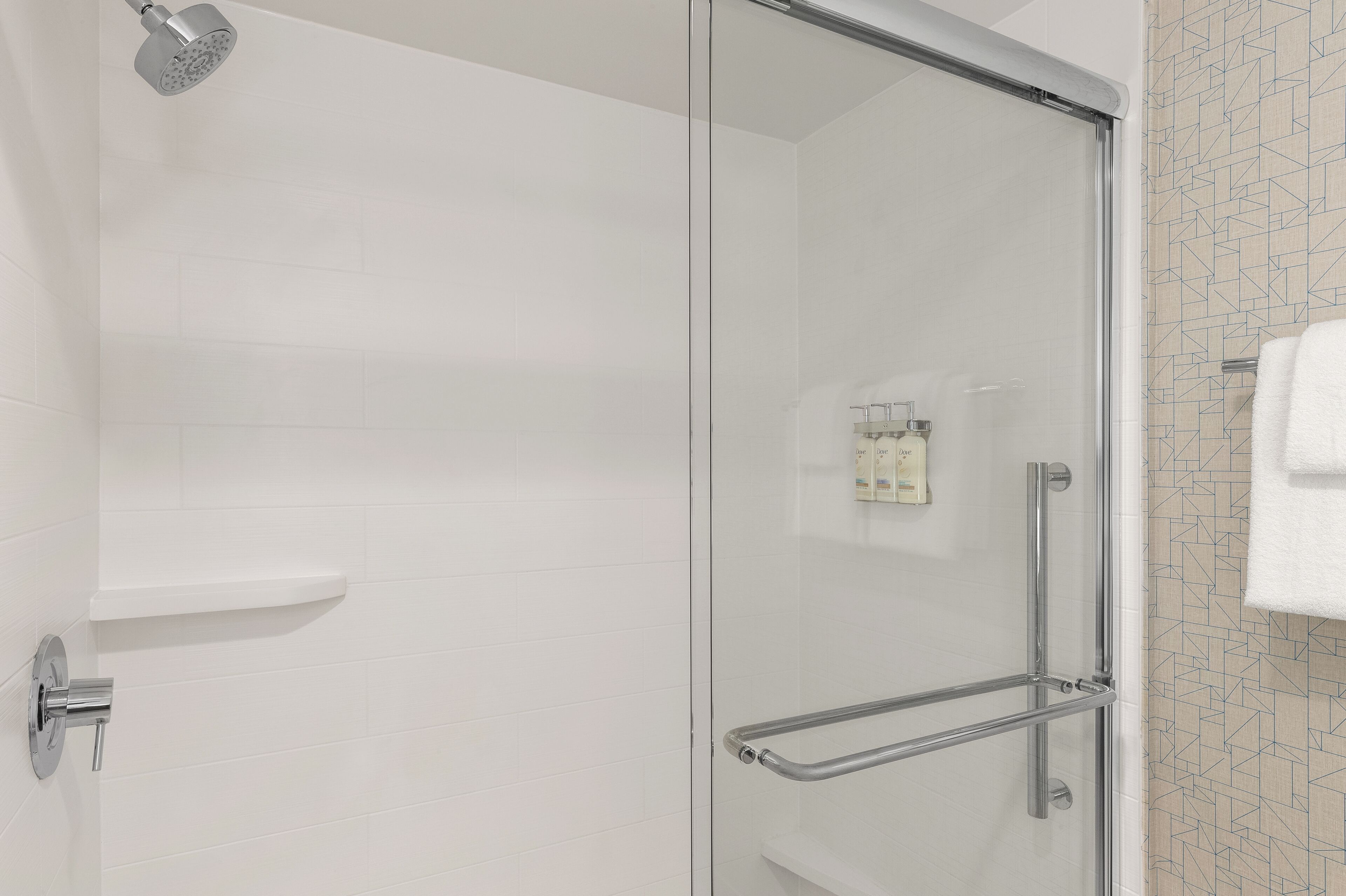 Une salle de bain moderne avec une douche à parois de verre, une barre d’appui et un porte-serviettes.