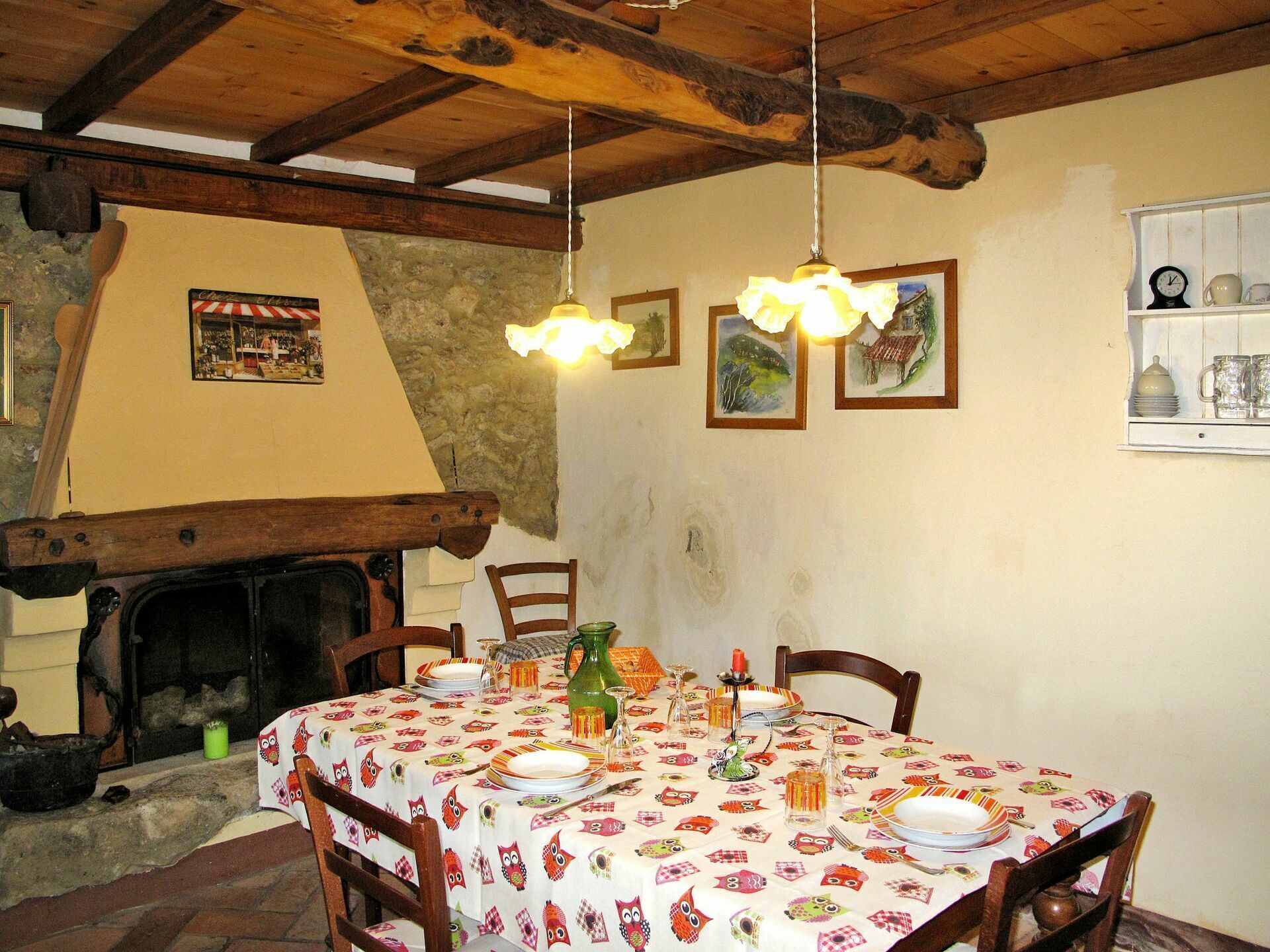 A rustic dining room with a fireplace, wooden beams, and a table set for a meal.
