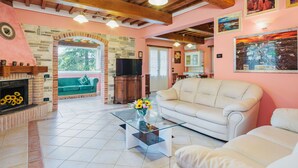 A cozy living room with a fireplace, a stone archway, a sofa, and a television. - Stunning private villa with private pool, WIFI, A/C, TV, terrace, pets allowed and panoramic view (Camaiore)