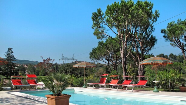 A pool area with red lounge chairs and striped umbrellas, surrounded by trees and a clear sky. - Stunning private villa with private pool, WIFI, A/C, TV, terrace, pets allowed and panoramic view (Camaiore)
