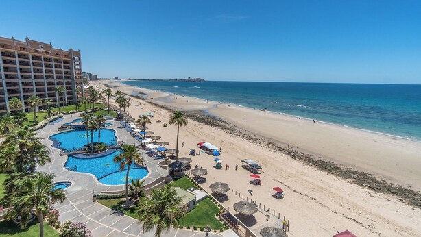 A resort with a large pool area, beach access, and a view of the ocean.