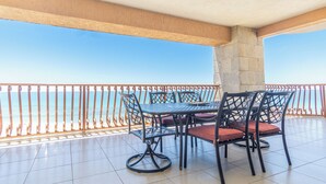 A balcony with a table and chairs, a clear view of the sea, and tiled flooring.