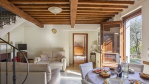 A spacious living room with a high ceiling, a dining area with a table set for a meal, and a view through an open door. - Beautiful private villa with A/C, WIFI, hot tub, private pool, TV, patio and pets allowed (Montecatini Terme)