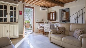A cozy living room with a wooden ceiling, a beige sofa, a dining table with chairs, and a cabinet with glass doors. - Beautiful private villa with A/C, WIFI, hot tub, private pool, TV, patio and pets allowed (Montecatini Terme)