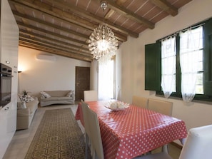 A cozy room with a wooden ceiling, a chandelier, a dining table with a red tablecloth, a sofa, and a window with green shutters. - Private Villa with A/C, private pool, hot tub, internet, TV, patio, pets allowed, panoramic view (Montecatini Terme)