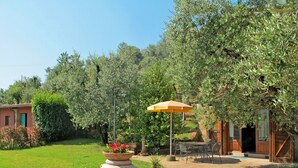A garden with a large terracotta pot, a patio area with outdoor furniture, and a wooden building in the background. - Private Villa with private pool, A/C, internet, hot tub, TV, patio, pets allowed, panoramic view (Montecatini Terme)