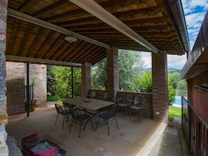 An outdoor patio with a wooden table and chairs, surrounded by brick walls and a view of greenery. - Private Villa with A/C, private pool, hot tub, internet, TV, patio, pets allowed, panoramic view (Montecatini Terme)