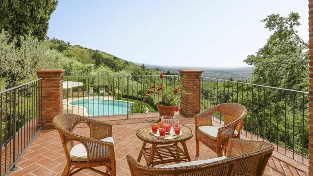 Eine Terrasse mit Korbmöbeln, einem Pool und einem schönen Ausblick.