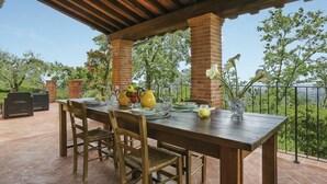 Eine Terrasss mit Holztisch, gedeckt für ein Essen, umgeben von Backsteinpfeilern und einer Pergola.