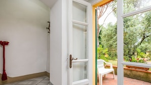 A staircase leading to a room with a white door, a red tassel, and a view of a garden with a white chair.