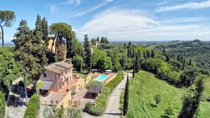 Una villa con piscina, rodeada de exuberante vegetación y colinas.