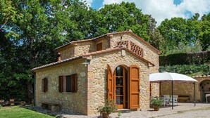 A stone house with a tiled roof, a wooden door, and a small patio with a table and chairs. - Wonderful private villa for 2 people with WIFI, TV and terrace (Volterra)
