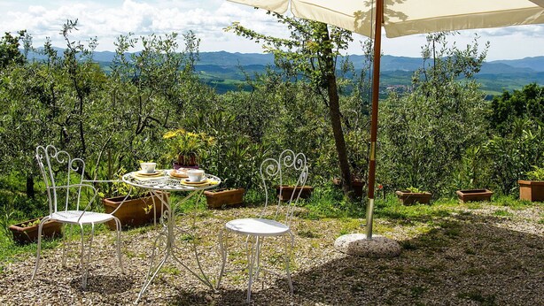 An outdoor dining area with a table and chairs, an umbrella, and a view of the countryside. - Wonderful private villa for 2 people with WIFI, TV and terrace (Volterra)
