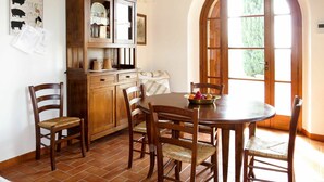 A dining area with a wooden table and chairs, a cabinet with glass doors, and a tiled floor. - Wonderful private villa for 2 people with WIFI, TV and terrace (Volterra)