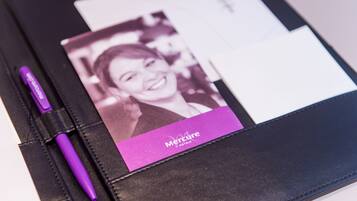 A black leather-bound notebook with a purple pen and a business card for Mercure Hotels.