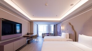 Una habitación de hotel moderna con una cama grande, un escritorio, un televisor de pantalla plana y un sofá.