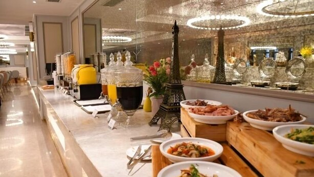Montaje de bufé con diferentes platos, una torre Eiffel decorativa y un interior moderno.