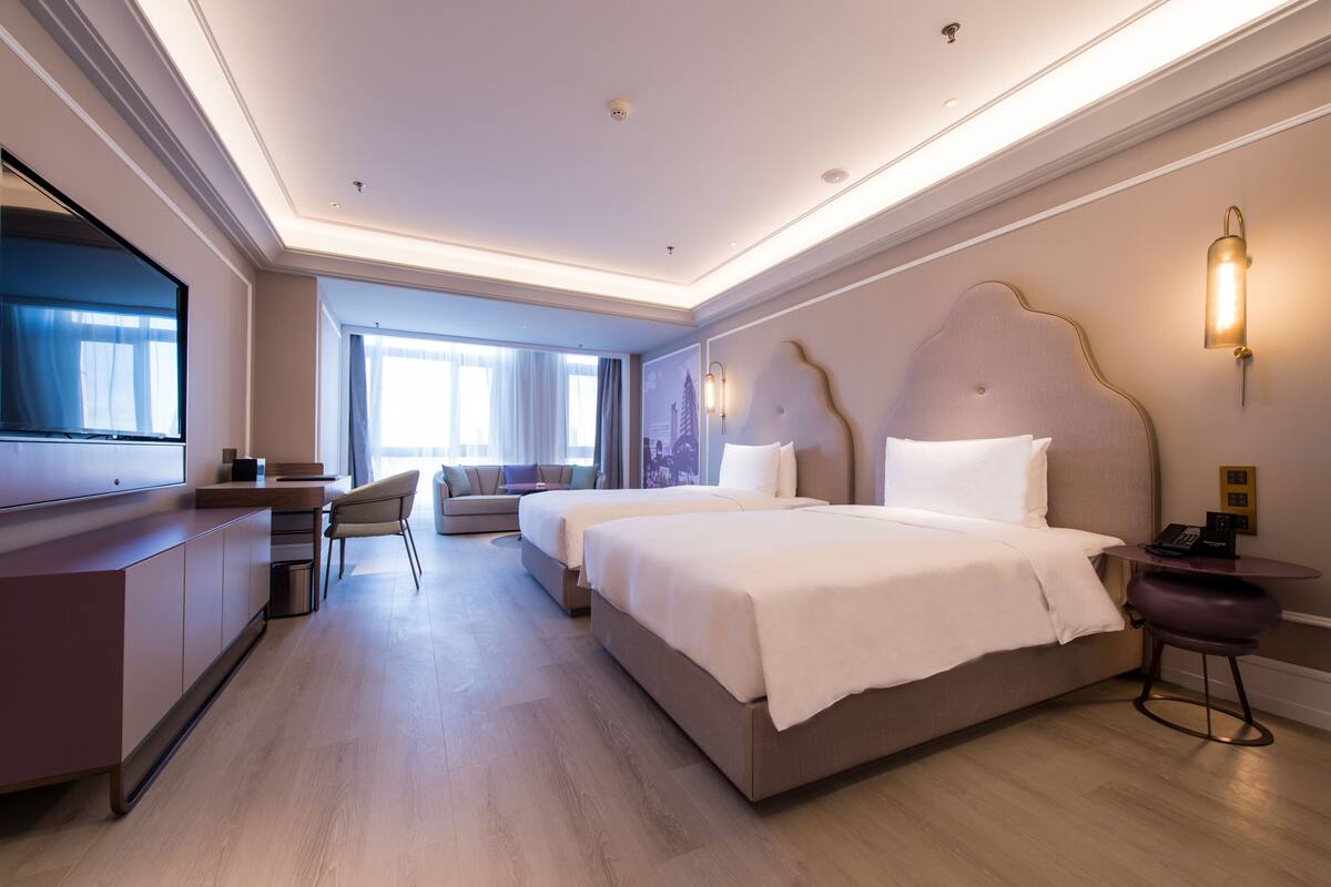 A modern hotel room with a large bed, a desk, and a TV.